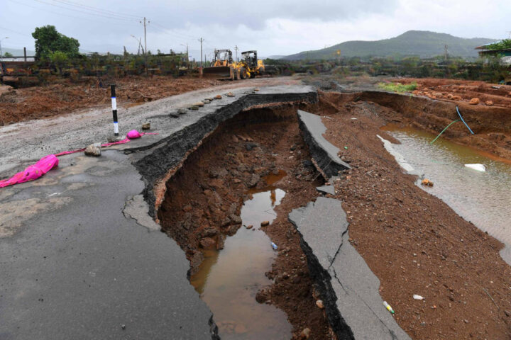 A damaged road showing cracks and erosion caused by floodwaters