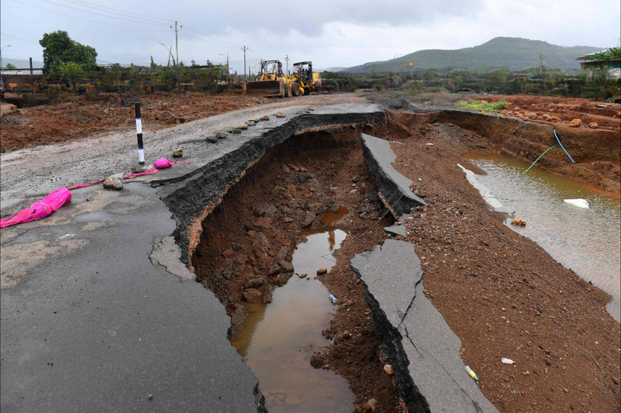 A damaged road showing cracks and erosion caused by floodwaters